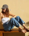 Theluto Meloe Cheetah leather sandals with ankle ties worn by a woman sitting on a wooden bench in casual attire