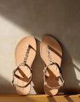 Theluto Meloe Cheetah leather sandals with leopard print straps and ankle ties on a neutral textured background