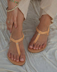 Theluto Meloe premium leather sandals in natural tan with ankle ties, worn on a white fabric background.