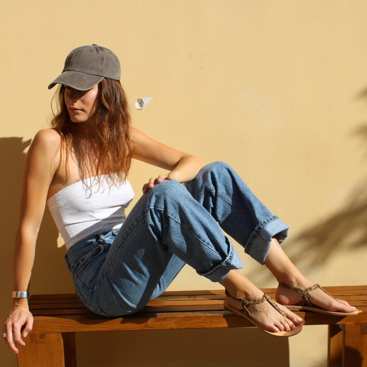 Theluto Meloe Cheetah leather sandals with ankle ties worn by a woman sitting on a wooden bench in casual attire