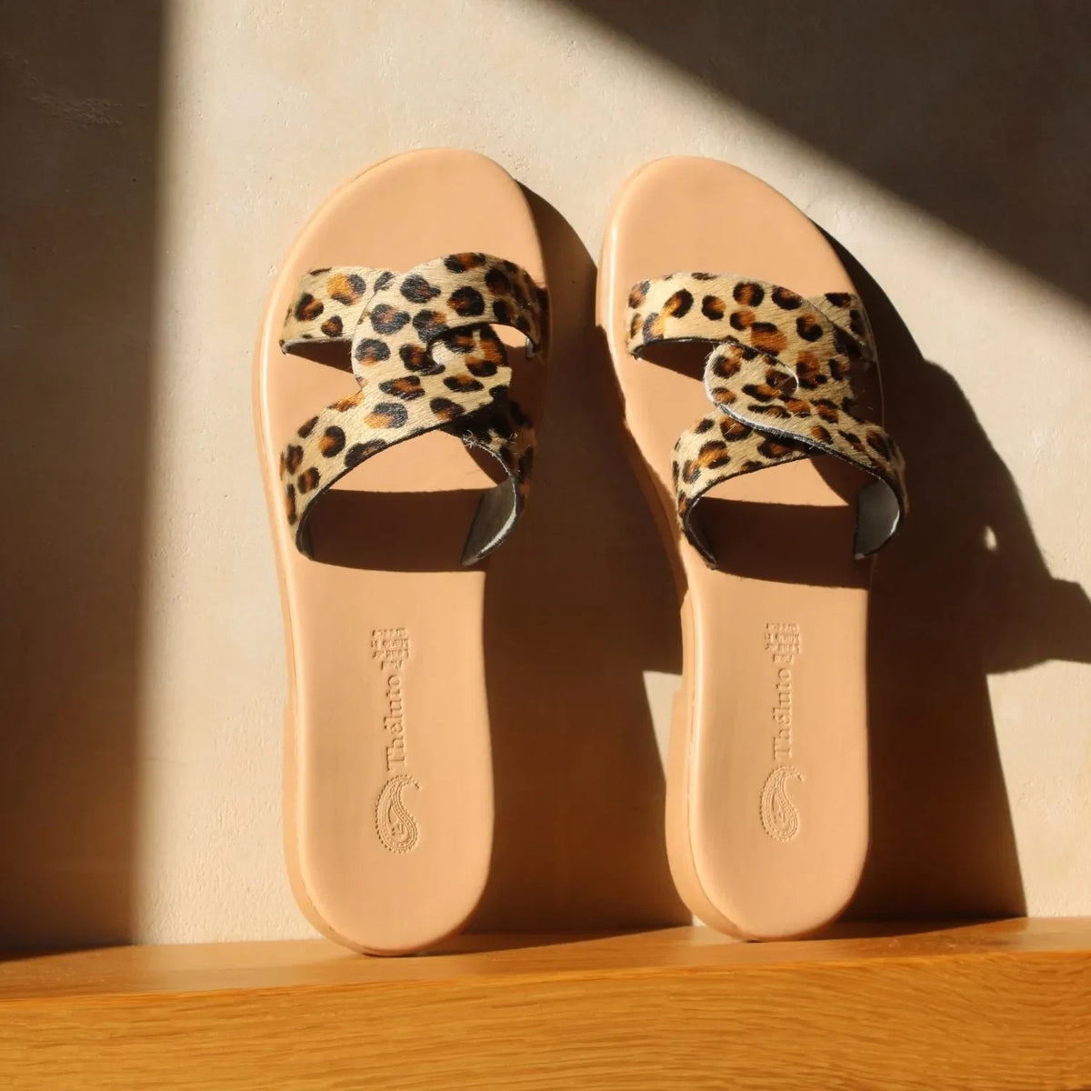 Theluto Prune Cheetah slip-on sandals featuring a tan leather sole and a crisscross strap with animal print texture.