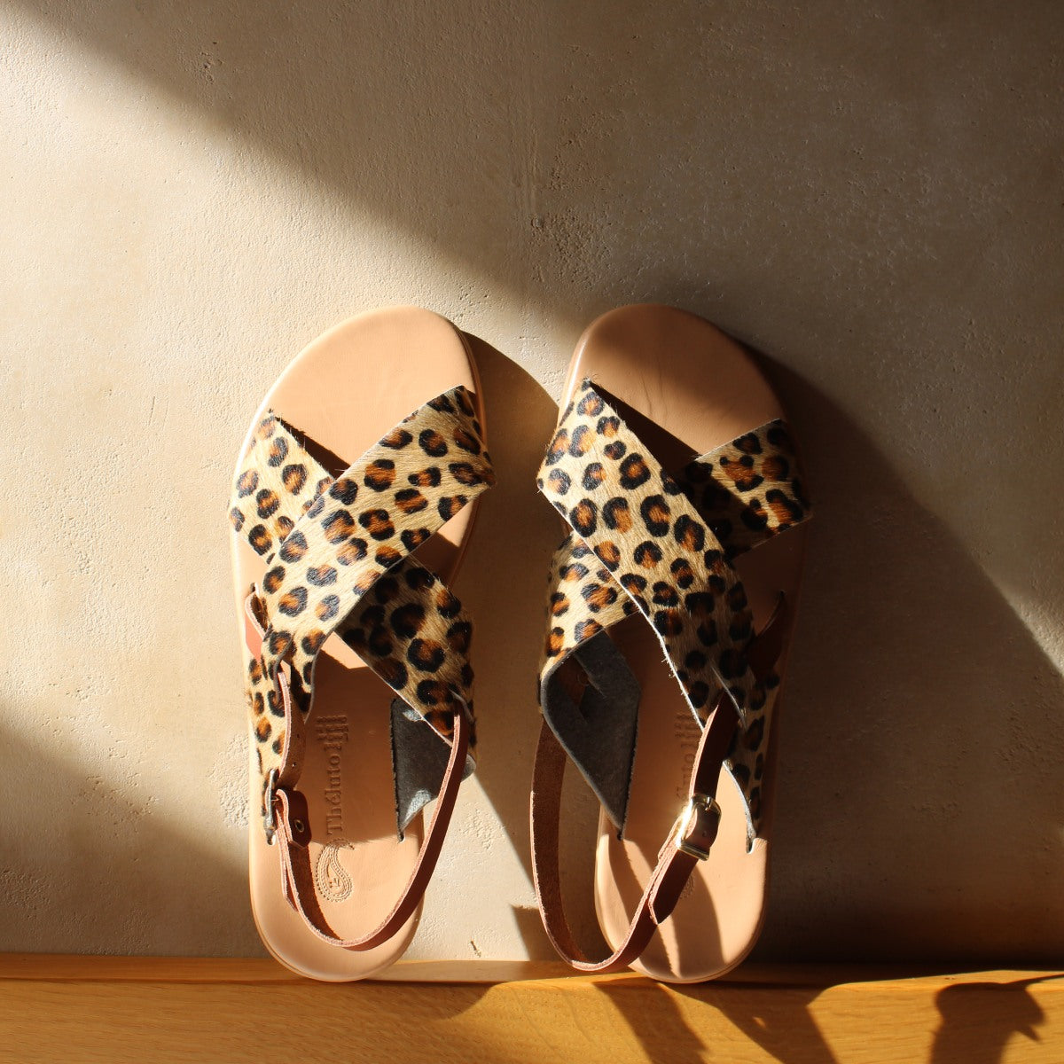 Theluto Tom Cheetah sandals featuring leopard print leather crisscross straps and a minimalist tan leather sole.