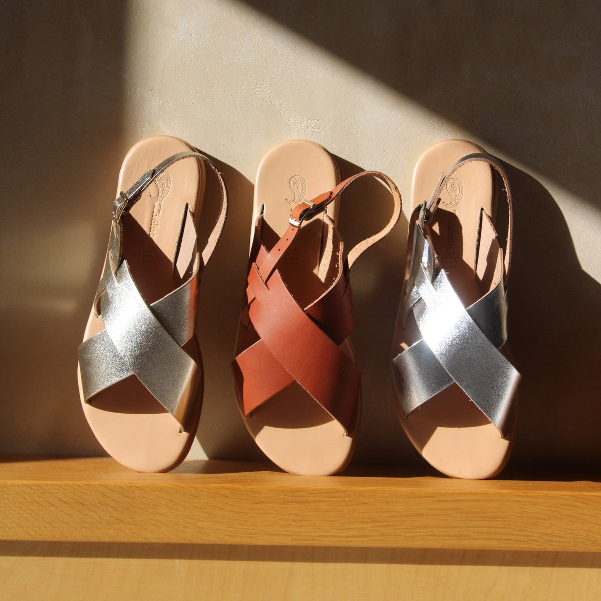 Theluto Tom minimalist leather sandals in silver and brown, featuring cross-strap design and adjustable buckles.