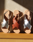 Theluto Tom minimalist leather sandals in silver and brown, featuring cross-strap design and adjustable buckles.