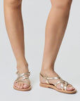 Theluto Valentine gold leather slip-on sandals with crisscross straps worn on feet against a neutral background