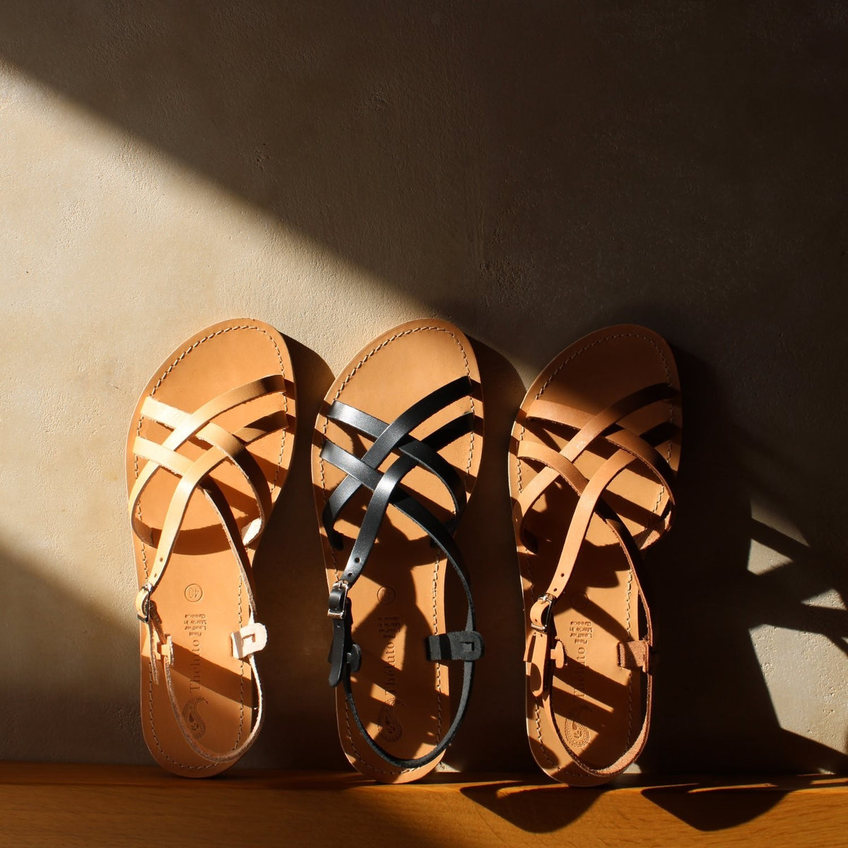 Theluto Valentine leather sandals in tan and black, featuring a slip-on design with crisscross straps and buckles.